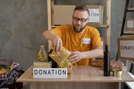 Volunteer man with box of food for poor. Donation concept. packing food in a cardboard box, helping and volunteeringの写真素材