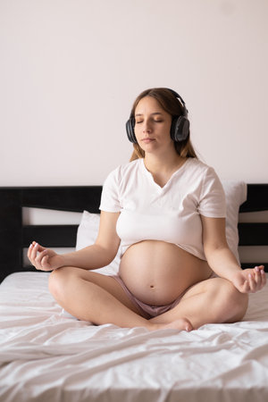 Motherhood meditation. pregnant woman meditating while sitting in lotus position on bedの写真素材