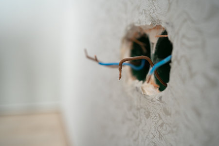 Several exposed electrical copper wires protruding from a whitewall. electrical wires and connector installed in plasterboard drywall for gypsum walls in apartment is under constructionの写真素材