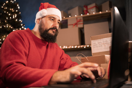 small business owner hindu freelance santa working at home office using computer packaging box for online marketing and christmas gifts, e-commerce for small and medium business, christmas saleの写真素材
