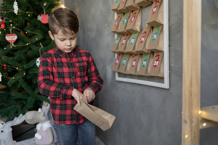 advent calendar hanging on the wall. child opens present. Christmas kids fun. craft bags with sweets. handmadeの写真素材
