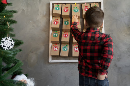 kid taking gift from advent calendar hanging on the wall, christmas kids fun, homemade giftsの写真素材