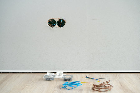 Unfinished electrical mains outlet socket, electrical wires and connector on floor, gypsum walls in apartment is under construction and remodelの写真素材