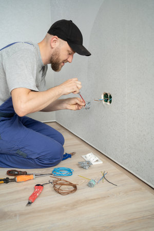 Electrician installing wall socket on the white wall indoorsの写真素材