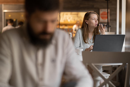 businesswoman working in cafe using laptop, freelancer work in coffee shop, man in foregroundの写真素材