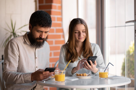 Couple having fun using smartphone at breakfast time, good morning and technologyの写真素材
