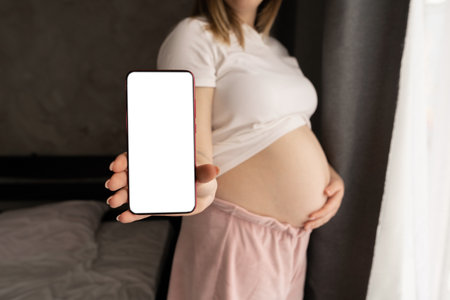 close up of pregnant woman hold modern smartphone with empty white blank mockup screen.Technology, motherhoodの写真素材