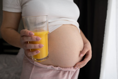 Close-up pregnant woman with glass of orange juice, pregnancy health and dietの写真素材