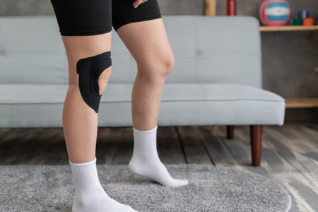 Female knees with physio tape on knee at home. Physiotherapyの写真素材