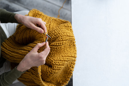 Close-up of female hands knitting wool sweater. Woman knits from thick yarn. Handmade clothes. The girl goes in for her hobbies. Knittingの写真素材