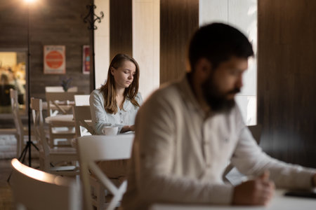 Young curious girl loves a bearded man looks with interest at a guy sitting next to him in a cafe, flirting in a public place, dating and love at first sightの写真素材