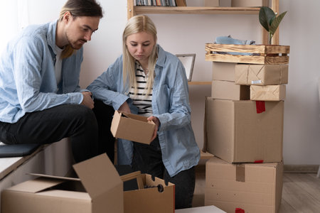 Unhappy woman client dissatisfied by parcel, looking in open cardboard damaged box, crushed fragile goods, bad delivery service. couple moving into a new homeの写真素材