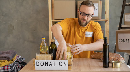 Portrait of smiling man volunteer packing a donation box in officeの写真素材
