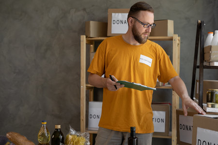 Young man wearing volunteer uniform working at charity center. Food donationの写真素材