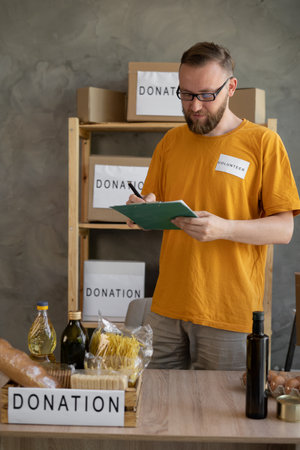 American volunteer going through donation checklist while working at food bank. charity, donation and volunteering conceptの写真素材