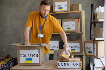 Volunteers collecting food donations in warehouse. Volunteer collect donations for Ukrainian refugees, humanitarian aid.の写真素材