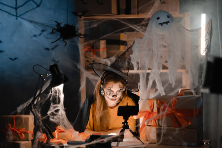 Startup small business entrepreneur or freelance caucasian woman in halloween makeup taking order online video call using smart phone. online marketing packaging box and shipping.の写真素材