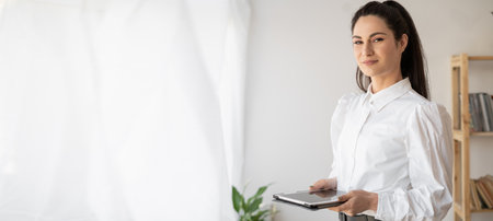 Successful businesswoman in stylish closes using tablet computer, standing in office working on business and marketing projects, looking at camera. Banner.の写真素材