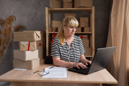 Online seller. Mature woman typing laptop keyboard checking online order, check goods stock delivery...