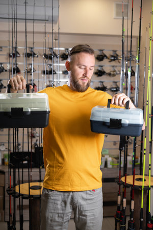 man choosing tackle boxes in a sports shop. Big or small boxの写真素材