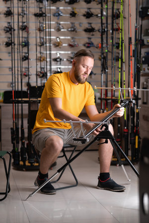 Man choosing fishing rod stand in sports shopの写真素材