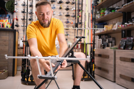 Man buyer choosing fishing rod stand in fishing shopの写真素材