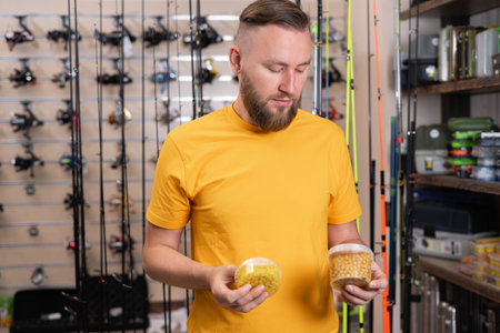 Handsome fisherman choosing fishing bait for fishing in the sports shop.の写真素材
