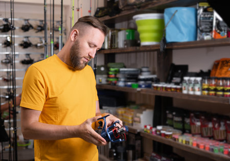 Man with spinning reel in sports shop. Fishing equipmentの写真素材