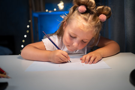 Cute little preschooler child girl drawing at home in the evening.の写真素材