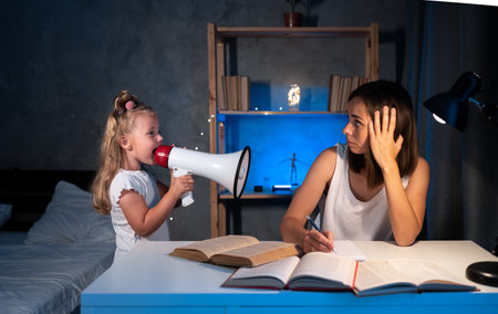little child yells at mom doing homework while sitting at the table, stress and anger, learning problem, girl child screaming and hysteria, homeschoolingの写真素材
