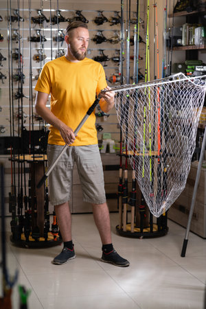 Fisherman choosing a landing net in a fishing shop.の写真素材