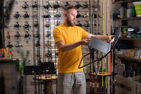 Man is buying a folding chair for fishing in a sport store, angler buyer in shop accessoriesの写真素材