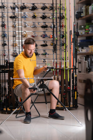 Man choosing fishing rod stand in sports shopの写真素材