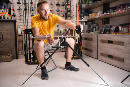 Man fisherman choosing fishing rod stand in sports shopの写真素材