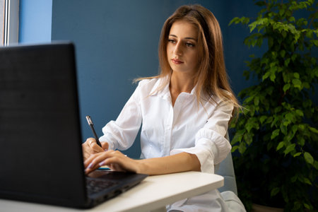 Beautiful young attractive woman at the cafe with a laptop having a coffee breakの写真素材