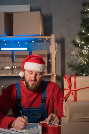 man entrepreneur small business owner is writes adress delivery at home in a small office. Prepares boxes for shipment. Big sale for Christmas. home office is seller of online store. start-up.の写真素材