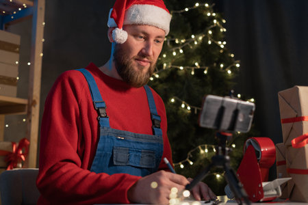 start up small business owner talking with customer on mobile phone at shop. Santa blogger talking on videoblog. freelance Santa Claus seller. Online selling Christmas sale e-commerceの写真素材