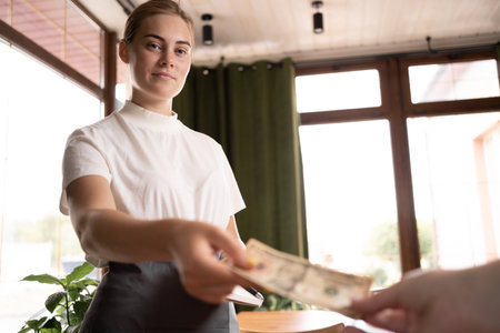 Waitress takes the tip. The waiter female receives a tip from the client at the cafe or restaurant. Serviceの写真素材