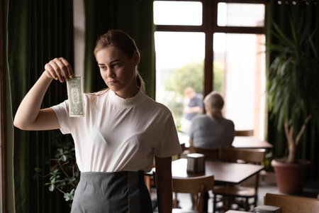 Professional sad waiter in restaurant with tips. little money from cafe customer. concept of service.の写真素材