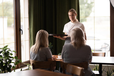 waiter holding aromatic coffee on tray bringing order to cafe guests, coffee shop worker give hot drinks to visitors. Serviceの写真素材