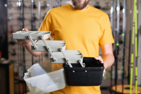 Man holding fishing tackle box in store, fisherman choosing accessoriesの写真素材