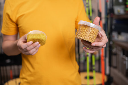 Man fisherman choosing bait in a fishing store, corn for fishの写真素材