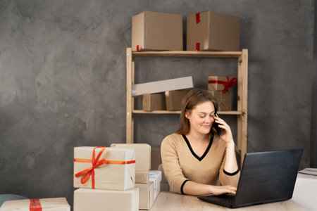 salesperson woman confirming orders from customer by phone. An e-commerce business owner looks at documents and talks on the phone in a store warehouse.の写真素材