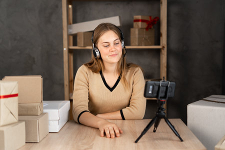 Startup woman entrepreneur happy after new order from customer with smartphone, mobile phone and delivery box on table, small business owner working from home office, SME, online shoppingの写真素材