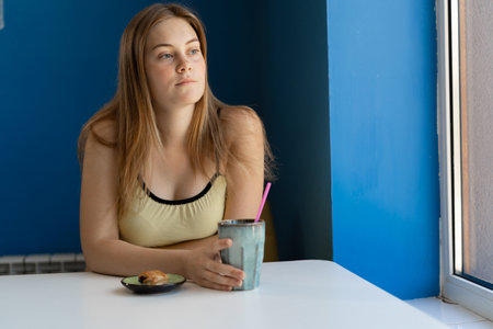 Beautiful blonde girl drinking tea or coffee in cafe. Beauty woman with the cup of beverage.の写真素材