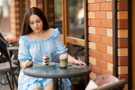 beautiful woman eating dessert in outdoor cafe, she has coffee break. people, street cafeの写真素材