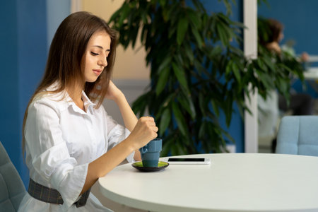 Young woman drinking coffee in a cafe and dreaming, thinking about plans for the future, serious girl drinking latte in a coffee shop, interiorの写真素材