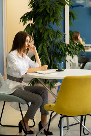 Young beautiful businesswoman writing in a notebook while studying in a cafeの写真素材