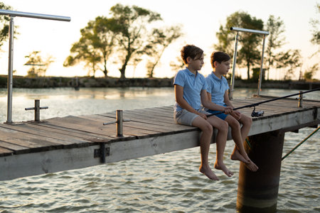 Two boys is fishing at sunset on the lake. Kids are playing on nature.の写真素材