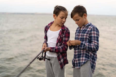 Portrait of two boys fishing at sunset on the lakeの写真素材